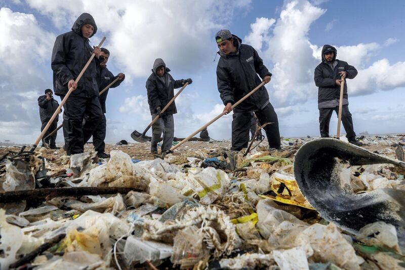 Workers clean the beach of the coastal town of Zouk Mosbeh, north of Beirut, on January 23, 2018 as garbage washed and piled along the shore after stormy weather. / AFP PHOTO / JOSEPH EID