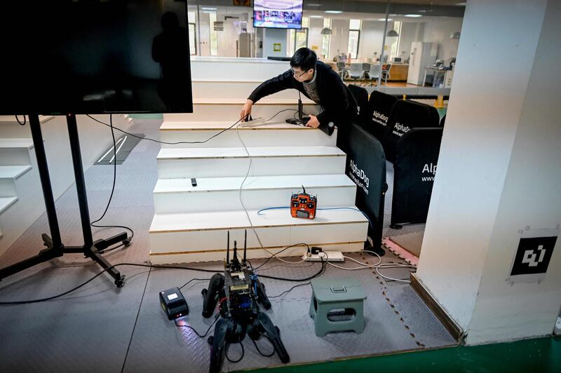 An engineer charging a quadruped robot in a workshop at the Weilan Intelligent Technology Corporation in Nanjing. Wang Zhao / AFP