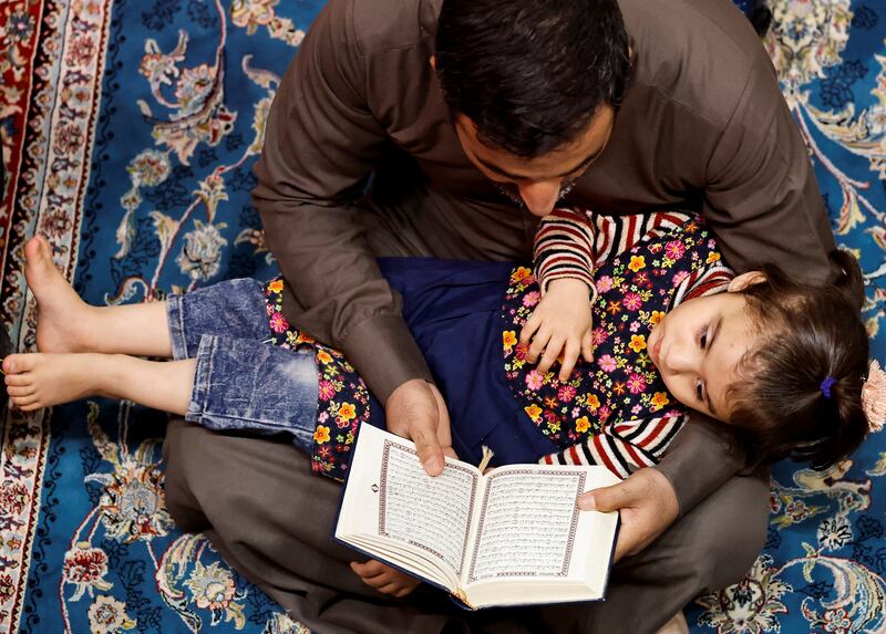 A man reads the Quran to a child