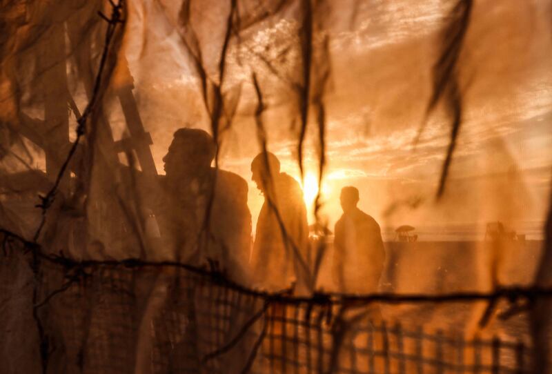 The silhouettes of Palestinian men appear behind the fabric of a beach tent, along the shore of Gaza City. AFP