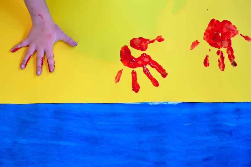 A Ukrainian child stamps her red-painted hand on the Ukrainian flag. EPA