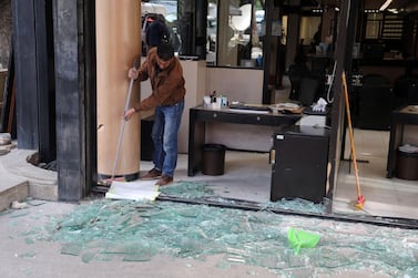 A worker clears up the shattered glass windows of a local Credit Libanais SAL bank branch in Beirut on Wednesday. Bloomberg