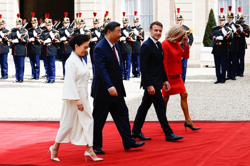 Mr Xi, Ms Peng, Mr Macron and Ms Macron walk past an honour guard to the palace. EPA