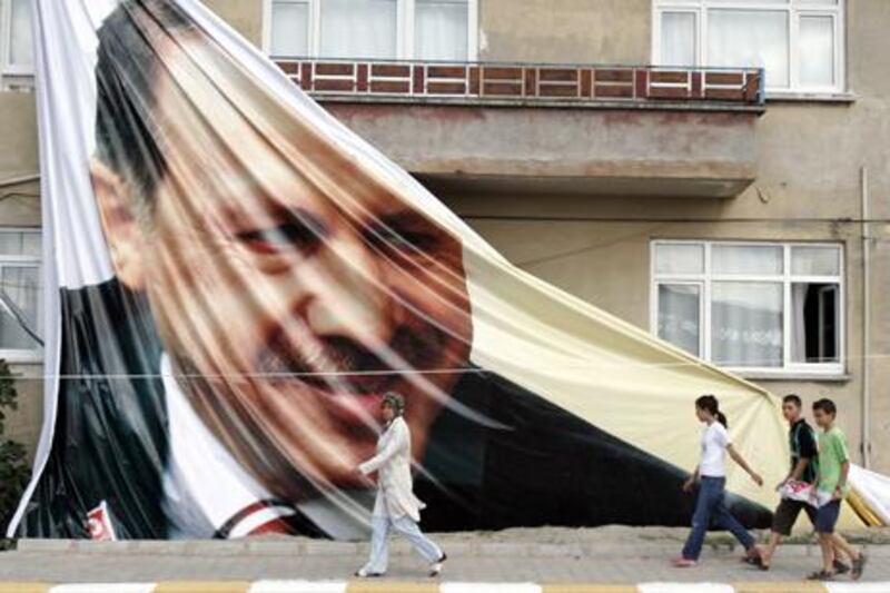 People walk past a giant poster of Recep Tayyip Erdogan, the Turkish prime minister, in Sakarya, Turkey. Saygin Serdaroglu / AFP