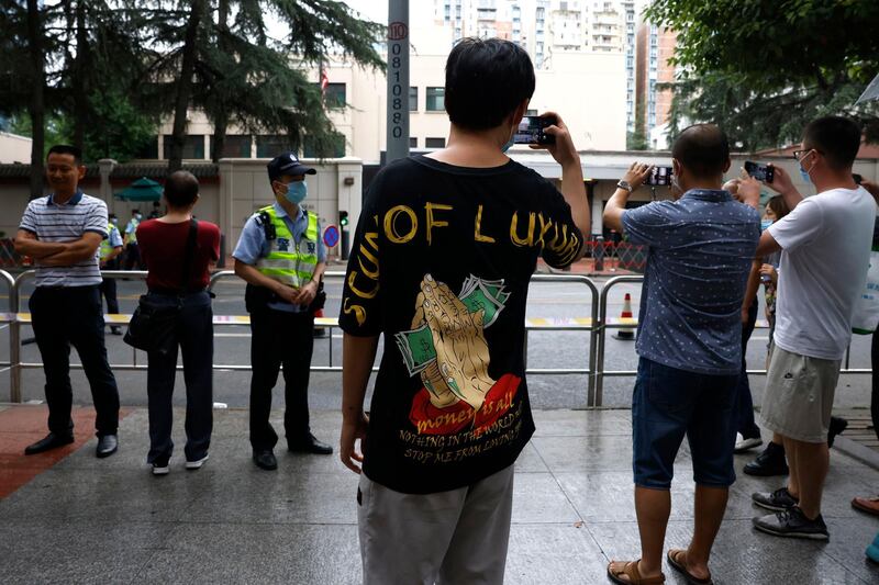 A man takes a photo with his phone in front of the US Consulate in Chengdu. AP Photo