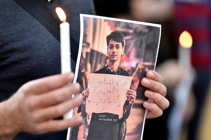 A Lebanese activist carries a candle and a picture for an Iraqi child who died during the uprising in Iraq during a gathering to support the children in the uprising in Iraq in front of the Iraqi embassy in Beirut.  EPA