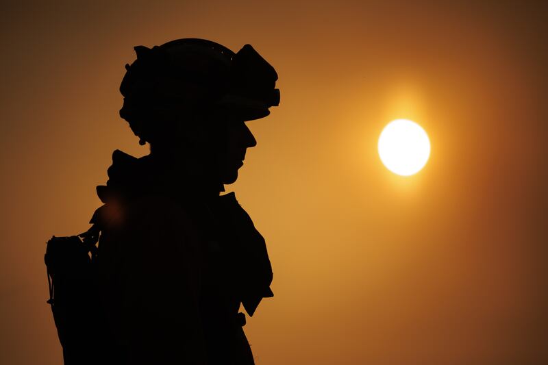 A firefighter looks on as a wildfire edges towards the village of Bejis. EPA