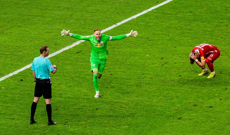 Referee Sascha Stegemann looks on as RB Leipzig's goalkeeper Peter Gulacsi celebrates and SC Freiburg's forward Ermedin Demirovic crumples after missing a decisive penalty kick during the German Cup Final football match at the Olympic Stadium in Berlin. The win gave Leipzig their first cup since the club was founded in 2009. AFP