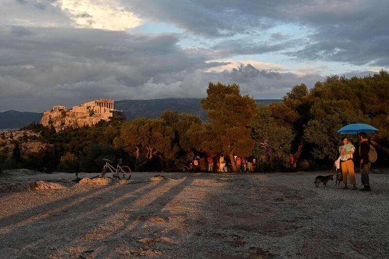 People visit the Pnyx Hill in Athens overlooking the ancient Acropolis on May 29, 2020 as Greece eases lockdown measures taken to curb the spread of the COVID-19 (the novel coronavirus). Greece announced a list of 29 countries deemed to fit the epidemiological profile , allowed to fly to Greece from 15 June as the country opens for tourists. / AFP / Louisa GOULIAMAKI
