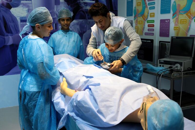 (L-R) Khalid Al Khushashi, 11, Abdulla Ghanem, 11, and Ali Al Khushashi, 9, take part in the OR surgery activity with science communicator Ammar Alhat. Christopher Pike / The National