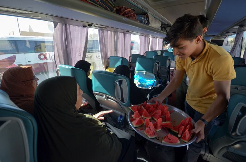 Volunteer Abdulrahman al Maani distributes watermelon slices to Hajj pilgrims leaving for Makkah, in Maan, Jordan. Reuters