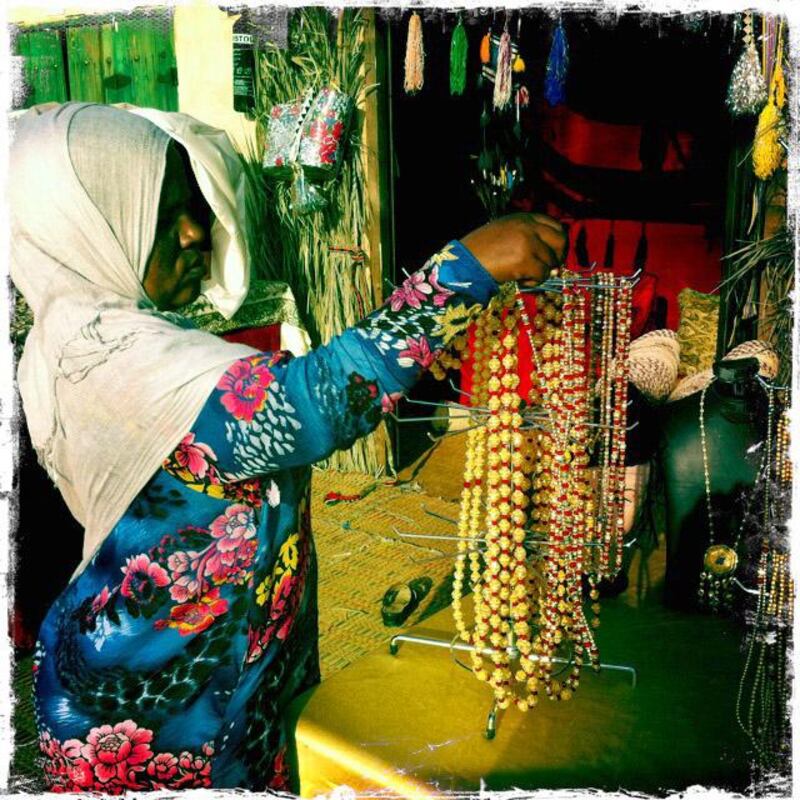 Day trip with friends to the Western Region and the Mazayin Dhafra Camel Festival, 220 kms west of Abu Dhabi on December 20, 2013.  A merchant organises her wares at the traditional souk.  Picture taken with the Hipstamatic app for the iPhone. Liz Claus / The National