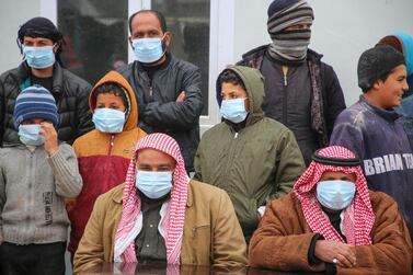 Displaced Syrians, some wearing protective masks, listen as medics hold an awareness campaign on how to be protected against the novel coronavirus pandemic. AFP