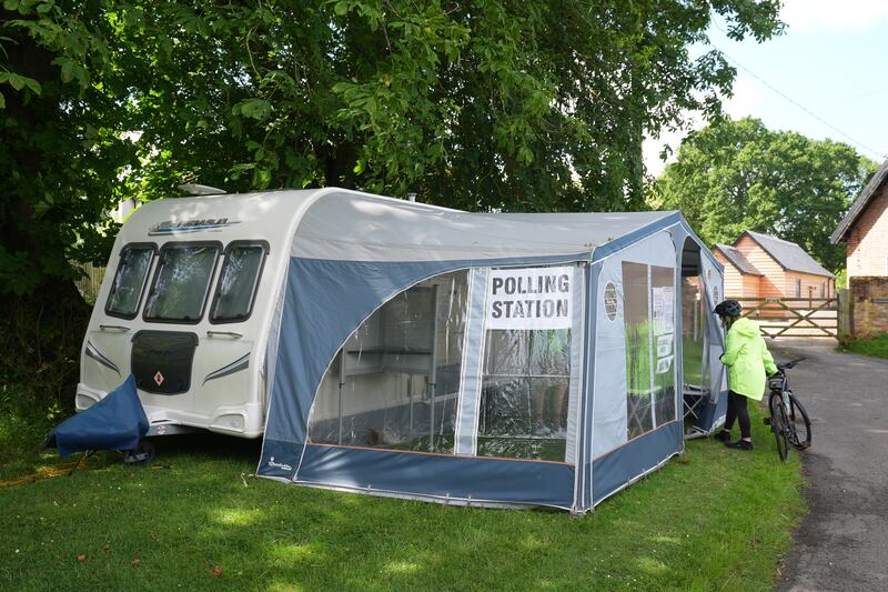 A voter stands outside a caravan used as a polling station in Carlton, Cambridgeshire. PA