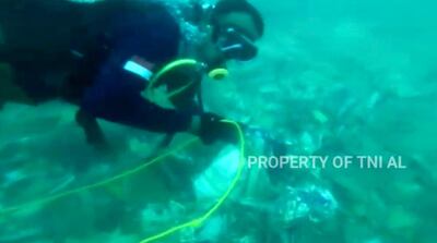 In this image made from undated video released by Indonesian Navy (TNI AL), divers is seen recovering debris strewn on the sea floor in Java Sea where Sriwijaya Air passenger jet crashed, in Indonesia. The search for the black boxes of a crashed Sriwijaya Air jet intensified Monday to boost the investigation into what caused the plane carrying 62 people to nosedive at high velocity into the Java Sea. (Indonesian Navy via AP)