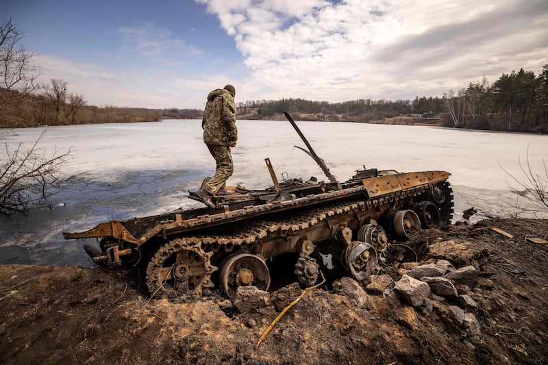 A Ukrainian serviceman stands near a destroyed Russian tank in the north-eastern city of Trostianets.  AFP