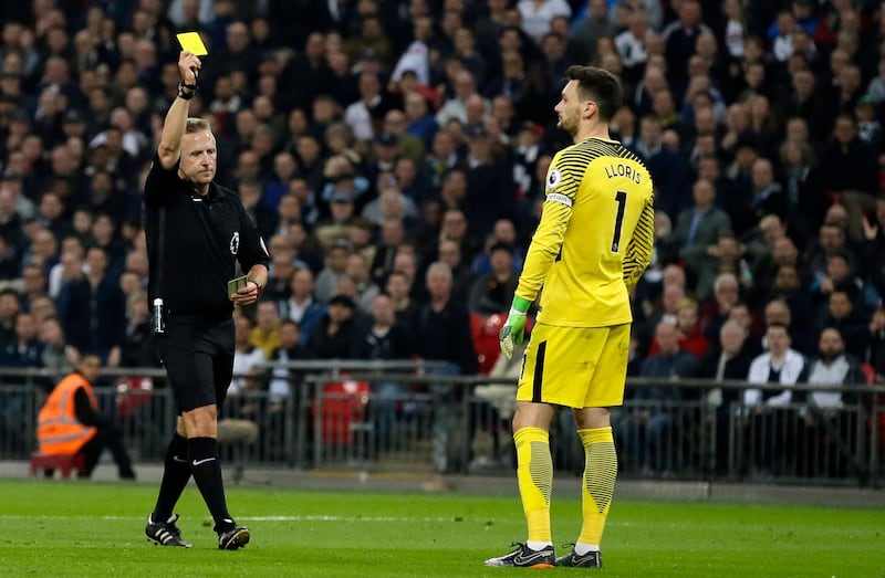 Referee Jon Moss shows a yellow card to Tottenham goalkeeper Hugo Lloris. Tim Ireland / AP Photo