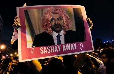 A Lebanese protester lifts a picture of Prime Minister Saad Hariri in a wig during a rally in downtown Beirut on the third day of demonstrations against tax increases and official corruption, on October 19, 2019. The writing "sashay away" refers to a catchphrase from a drag queen TV show meaning "leave".  / AFP / IBRAHIM AMRO
