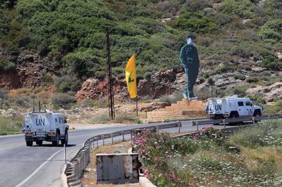 UN peacekeeping vehicles pass a Hezbollah flag and a statue of the late Iranian General Qassem Soleimani, as they patrol on a road along the Lebanese-Israeli border town of Naqoura. AP 