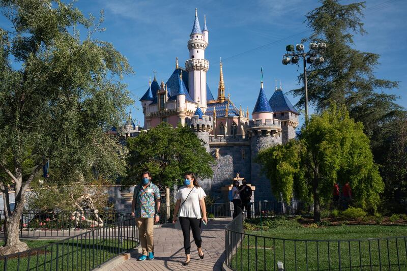 Guests wearing protective masks walk past Sleeping Beauty Castle during the reopening of the Disneyland theme park in Anaheim, California, U.S., on Friday, April 29, 2021. Walt Disney Co.'s original Disneyland resort in California is sold out for weekends through May, an indication of pent-up demand for leisure activities as the pandemic eases in the nation's most-populous state. Photographer: Bing Guan/Bloomberg