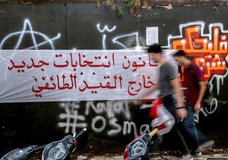 Protesters pass by a banner with Arabic words read 'A new election law outside the sectarian restriction'  in front the Government palace in downtown Beirut. EPA