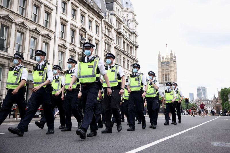 Police officers walk along Whitehall during an anti-lockdown and anti-vaccine protest in central London. Reuters