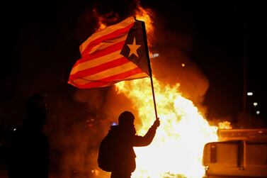 A protester waving a Catalan pro-independence "Estelada" flag stands next to a burning barricade during a protest called by Catalan separatist movement Democratic Tsunami outside the Camp Nou stadium. AFP