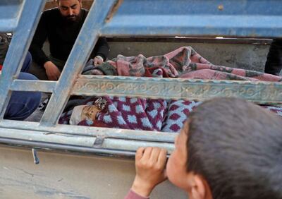 A Syrian boy looks at the body of a child during a funeral in the the village of Atareb in the northern Syrian province of Aleppo on March 21, 2021, for civilians killed in regime artillery fire on a hospital. Regime artillery fire killed five civilians including a child when it hit a hospital entrance in Syria's last major rebel bastion of Idlib, the Syrian Observatory for Human Rights said. / AFP / AAREF WATAD
