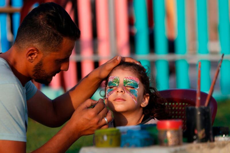Osama, a Palestinian artist, paints the face of a young girl in Gaza City. AFP