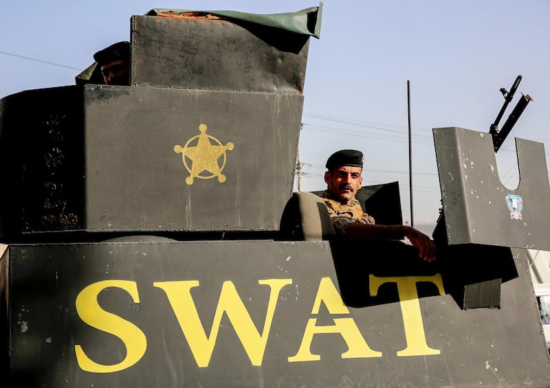 An Iraqi SWAT security forces member, affiliated to the Interior Ministry, mans a turret in an armoured vehicle parked outside an ongoing blaze in the country's biggest ballot warehouse, where votes for the eastern Baghdad district were stored. Sabah Arar / AFP