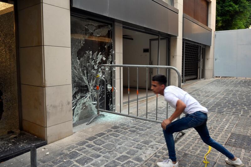 A metal barrier is used to smash windows during a protest against power cuts, the high cost of living, and the low purchasing power of the pound near the Lebanese Parliament in Beirut. EPA