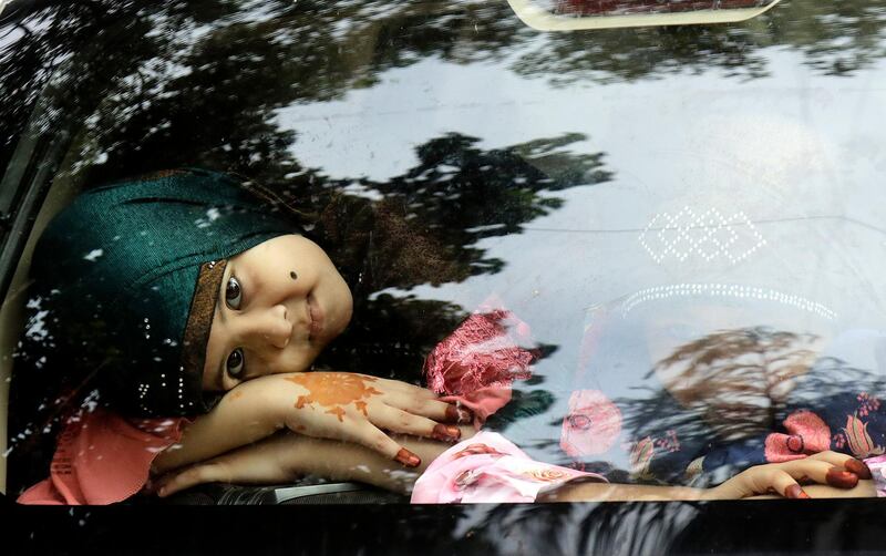 Muslim girls with henna-decorated hands look out from a car on Eid in Mumbai, India, Saturday, Aug. 1, 2020. Eid al-Adha, or the Feast of the Sacrifice, is marked by sacrificing animals to commemorate the prophet Ibrahim's faith in being willing to sacrifice his son. (AP Photo/Rajanish Kakade)