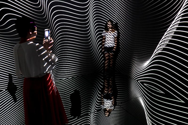 A woman is beamed by light pattern as she poses at an art installation titled Infinity Room. Andy Wong / AP photo