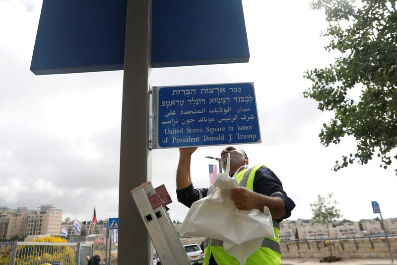 A worker uncovers a sign, dedicating a traffic circle in honor of US President Donald Trump, near the location of the new US embassy in Jerusalem, on May 13, 2018. Ronen Zvulun / Reuters