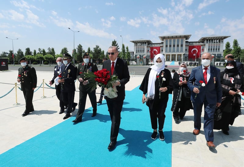 Turkey's President Recep Tayyip Erdogan and family members of coup victims walk to place a floral tribute at the "Martyrs Monument" outside his presidential palace, in Ankara, Turkey. AP