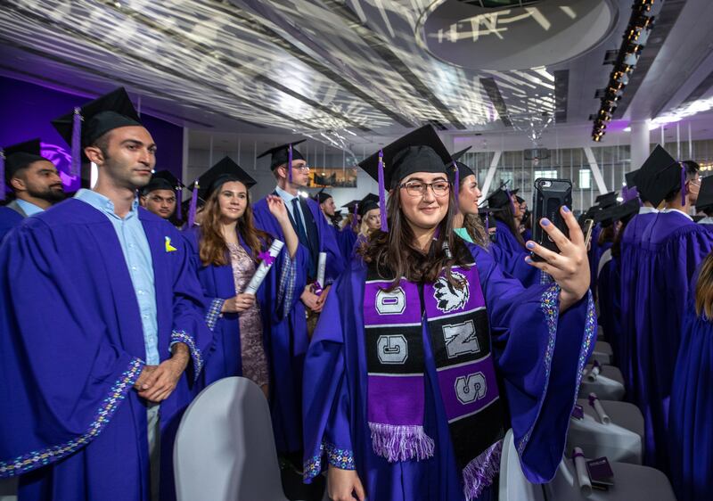 A happy graduate takes a selfie.