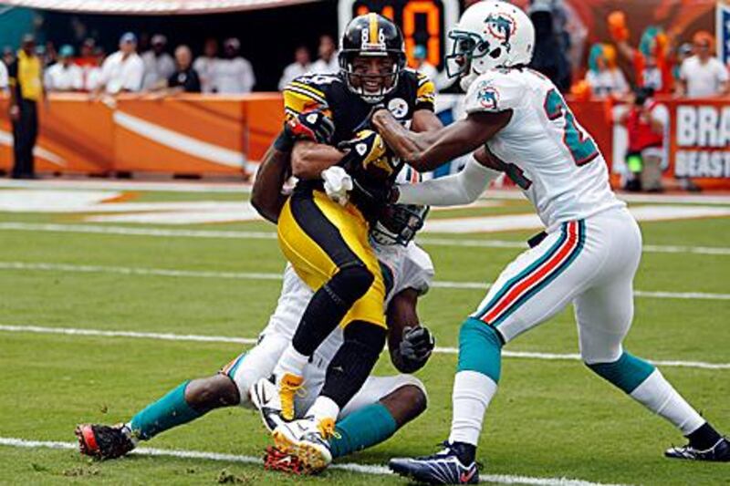 Hines Ward, No 86, of the Steelers, gets tackled by the Dolphins’ Sean Smith, No 24, on Sunday.