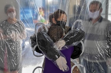 (FILES) In this file photograph taken on June 13, 2020, Elisabete Nagata (top) hugs her 76-year-old sister-in-law Luiza Nagata, through a transparent plastic curtain at a senior nursing home in Sao Paulo, Brazil, amid the novel coronavirus (Covid-19) pandemic. The coronavirus has upended everyday life in the six months since the crisis was declared a pandemic by the World Health Organization (WHO). While our understanding of the new respiratory disease has steadily increased since it was first detected in China last year, what lies ahead over the next half-year remains unknown. / AFP / NELSON ALMEIDA