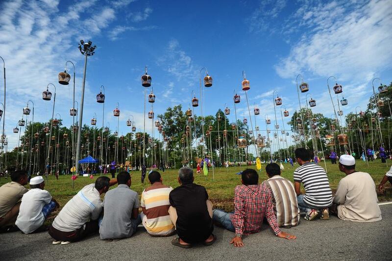 People sit and watch birds hoisted on poles in their cages during a bird-singing contest in Thailand’s southern province of Narathiwat. Over one thousand birds from Thailand, Malaysia and Singapore take part in the annual contest. Madaree Tohlala / AFP