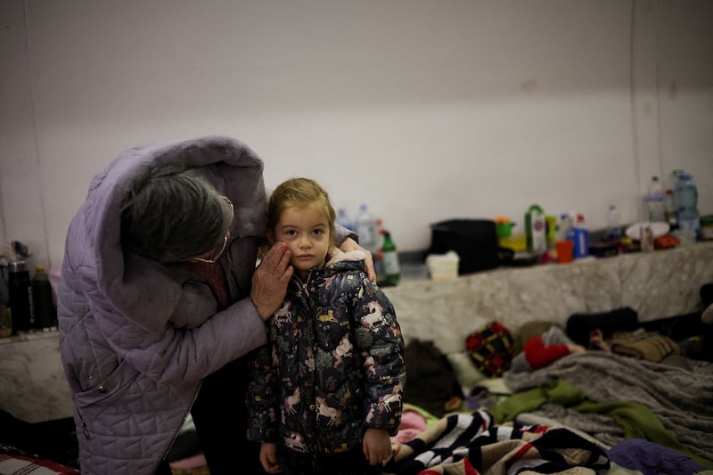 An elderly woman comforts a child as they take shelter inside an underground station in Kyiv. Reuters