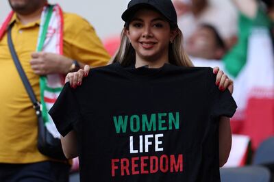 A woman holds a t-shirt with a slogan that reads 'Woman life freedom' during a football match at the Qatar World Cup. AFP