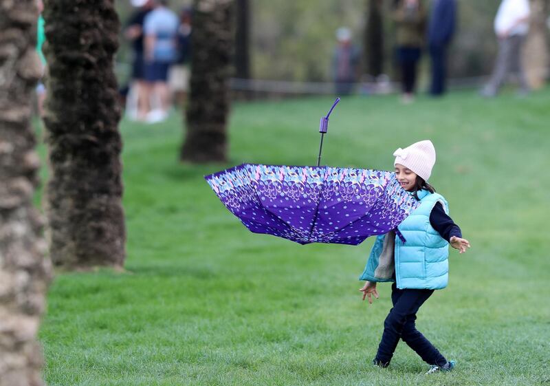 Dubai, United Arab Emirates - Reporter: Paul Radley and John McAuley: Young golf fans struggle to hold onto their umbrellas in the windy wet conditions on the 16th hole on the 4th and final day of the Omega Dubai Desert Classic. Sunday, January 26th, 2020. Emirates Golf Club, Dubai. Chris Whiteoak / The National