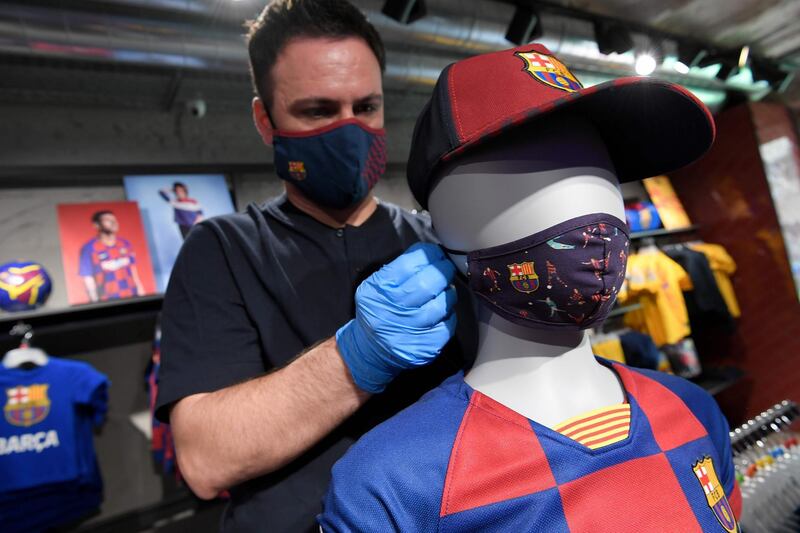 An employee places a mask with the logo of FC Barcelona on a mannequin at the FC Barcelona store. AFP