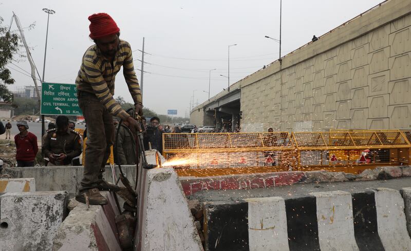Workers construct barricades as security personnel stand guard at the Delhi Ghazipur border. EPA