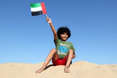 Hussein, 8, waves his flag in the desert on National Day. Chris Whiteoak / The National