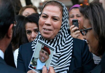 Latifa Ibn Ziaten offers a picture of her son, French paratrooper Imed Iban Ziaten killed by Mohamed Merah, to France's President Francois Hollande (L) during a ceremony commemorating the victims of terrorism at the Invalides in Paris, on September 19, 2012. AFP PHOTO / POOL / FRANCOIS MORI (Photo by FRANCOIS MORI / POOL / AFP)