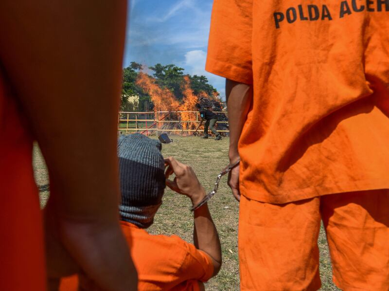 Arrested drugs smuggling suspects watch about two tonnes of marijuana and 10 kilograms of methamphetamine in Banda Aceh, Indonesia. Chaideer Mahyuddin / AFP Photo