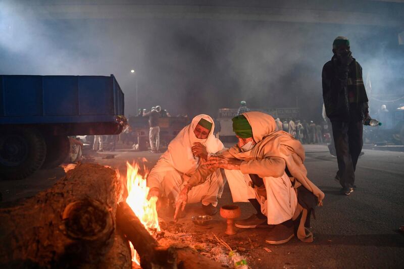 Farmers warm up around a bonfire under a bridge near a police road block stopping them from marching to New Delhi to protest against the central government's recent agricultural reforms.  AFP