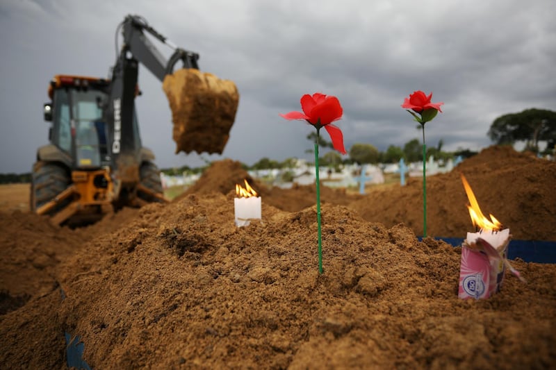 Candles and flowers are placed by a relative on the grave of Joao Marinho, 76, who passed away due to Covid-19 at the Parque Taruma cemetery in Manaus, Brazil. Reuters