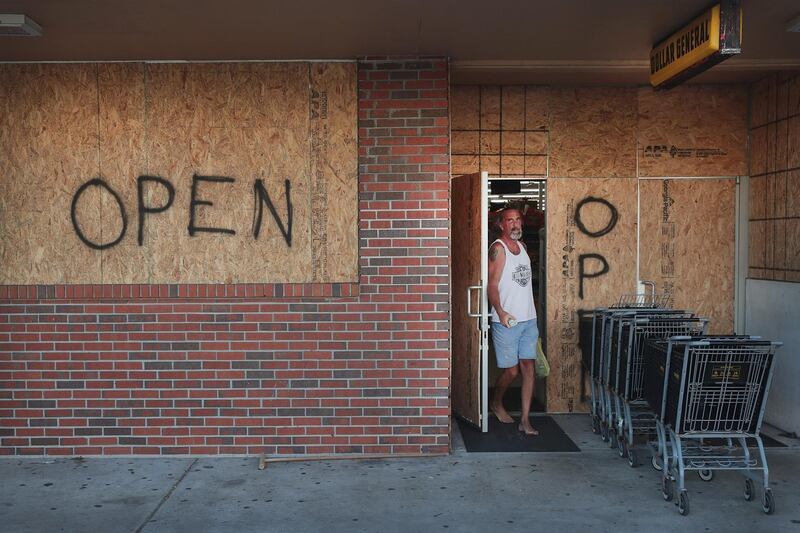 Shoppers grab supplies at a boarded-up strip mall in preparation for Hurricane Dorian on August 31, 2019 in Indialantic, Florida. Dorian, once expected to make landfall near Indialantic as a category 4 storm, is currently expected to turn north and stay off of the Florida coast, lessening the impact on the area.   Scott Olson/Getty Images/AFP